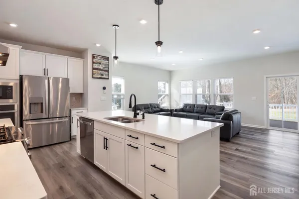 a large kitchen with stainless steel appliances granite countertop a refrigerator a sink dishwasher a oven and a large window with wooden floors
