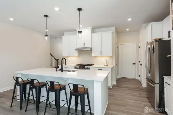 a kitchen with stainless steel appliances granite countertop a stove a refrigerator a oven a sink with a dining table and chairs