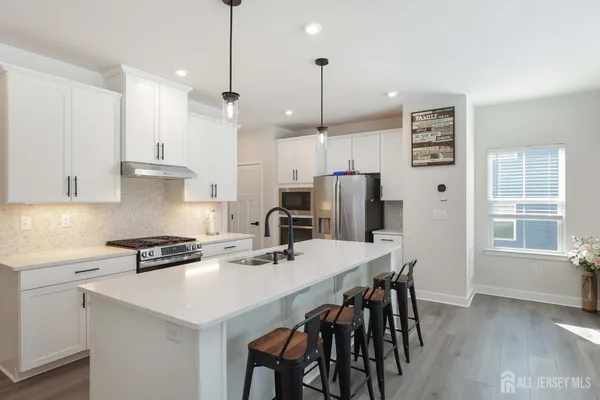 a kitchen with stainless steel appliances kitchen island a table chairs and a refrigerator