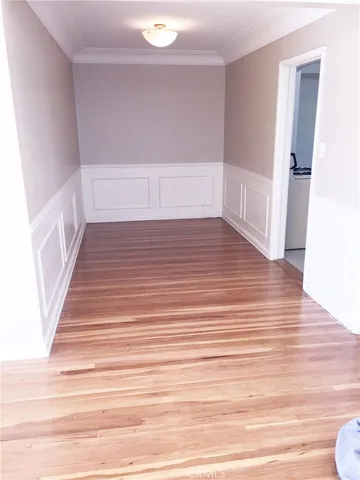 a view of an empty room with wooden floor and stairs