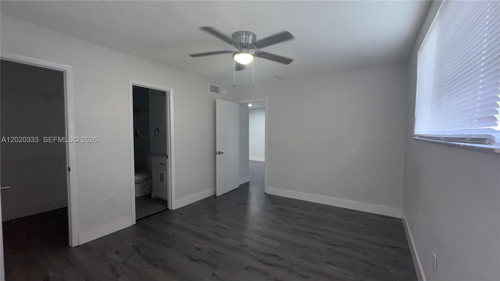 11309 Southwest 200th Street, Unit 103C Miami, FL 33157 - Photo 12 of 18 an empty room with wooden floor and a ceiling fan