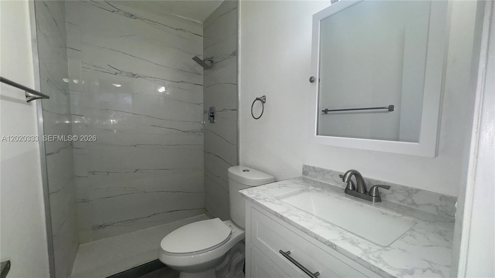 11309 Southwest 200th Street, Unit 103C Miami, FL 33157 - Photo 15 of 18 a bathroom with a granite countertop toilet a sink and a mirror