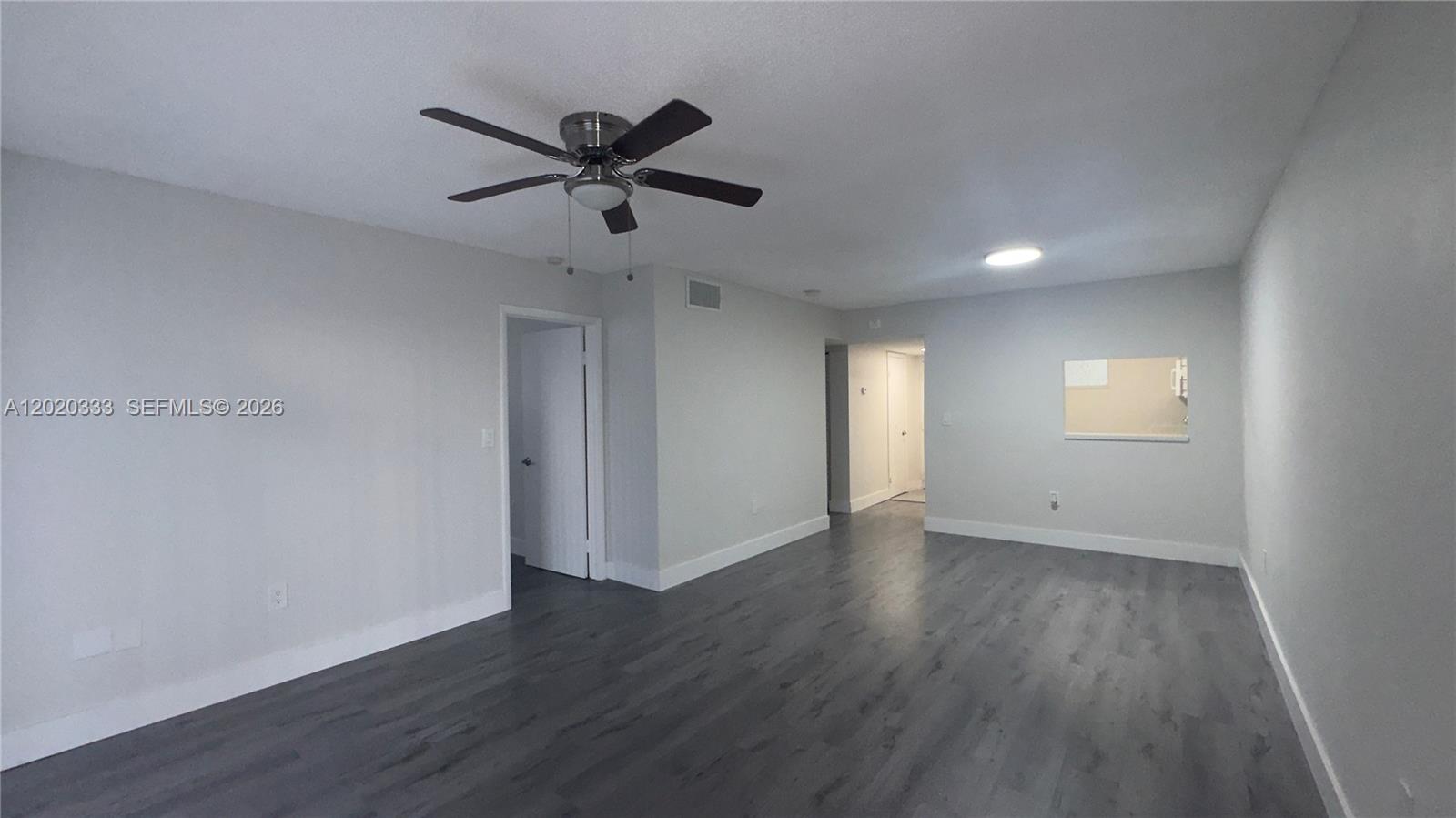 11309 Southwest 200th Street, Unit 103C Miami, FL 33157 - Photo 6 of 18 a view of an empty room with wooden floor and a ceiling fan