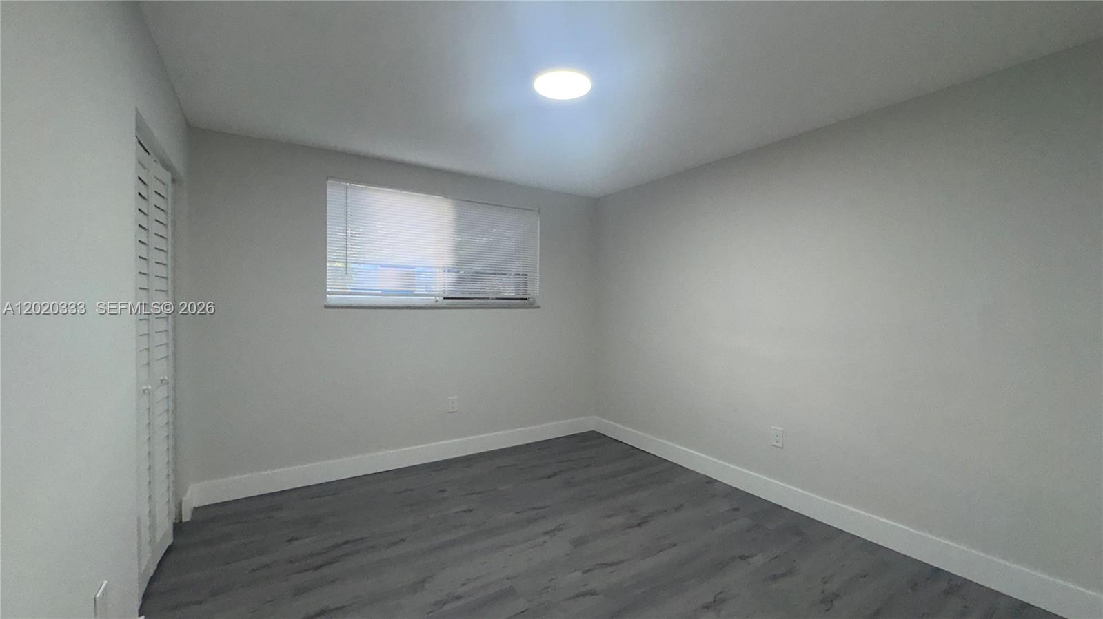 11309 Southwest 200th Street, Unit 103C Miami, FL 33157 - Photo 9 of 18 an empty room with wooden floor and windows