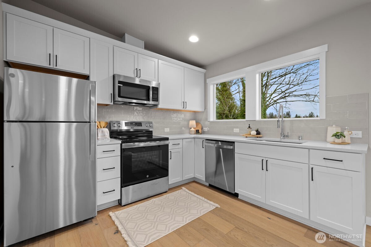 7853 South 132nd Street Seattle, WA 98178 - Photo 34 of 40 a kitchen with stainless steel appliances white cabinets a sink and a refrigerator