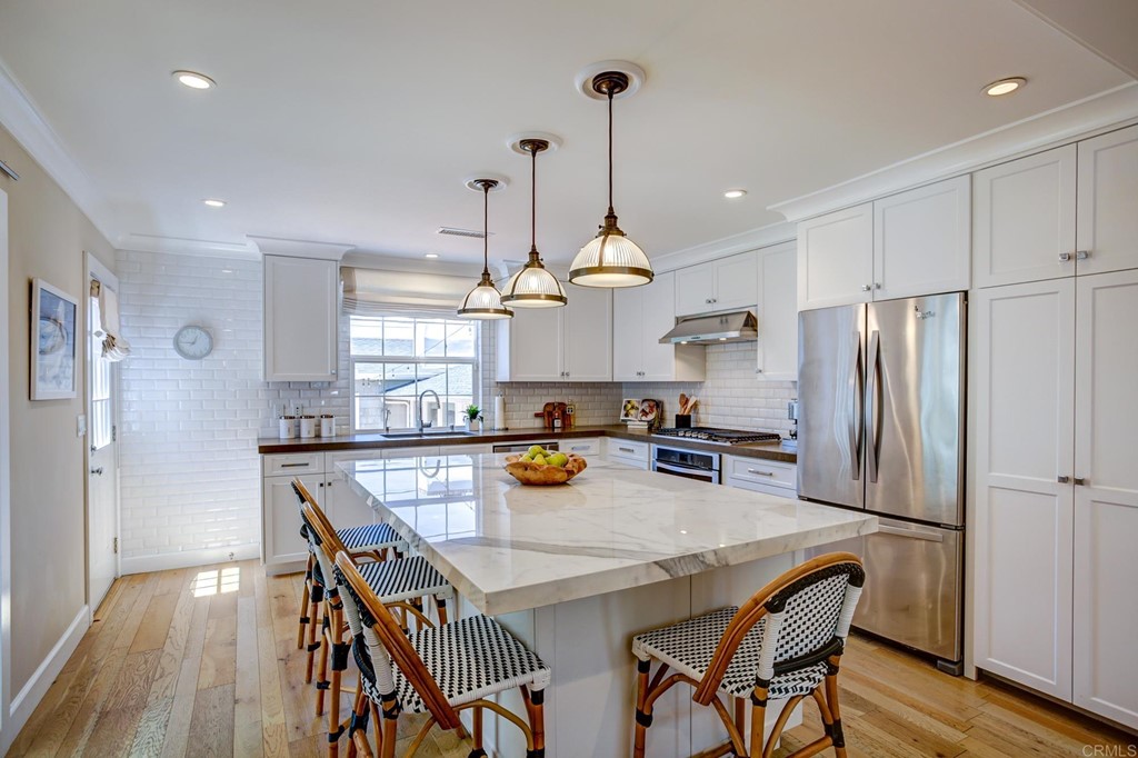 7936 Paseo Del Ocaso La Jolla, CA 92037 - Photo 12 of 43 a kitchen with stainless steel appliances granite countertop a dining table chairs refrigerator and wooden floor