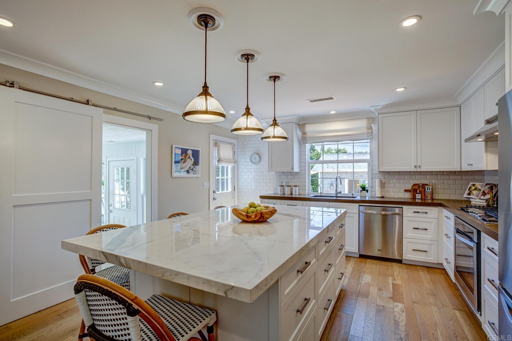 7936 Paseo Del Ocaso La Jolla, CA 92037 - Photo 13 of 43 a kitchen with a stove a refrigerator a sink a dining table and chairs with wooden floor
