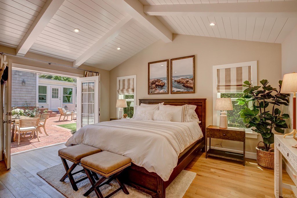 7936 Paseo Del Ocaso La Jolla, CA 92037 - Photo 29 of 43 a spacious bedroom with a bed a table and potted plant with wooden floor