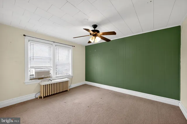 an empty room with chandelier fan and windows