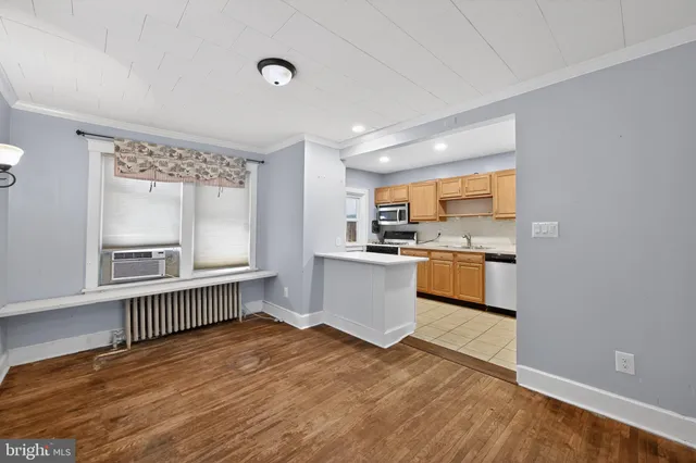 a kitchen with stainless steel appliances kitchen island wooden floors and white cabinets