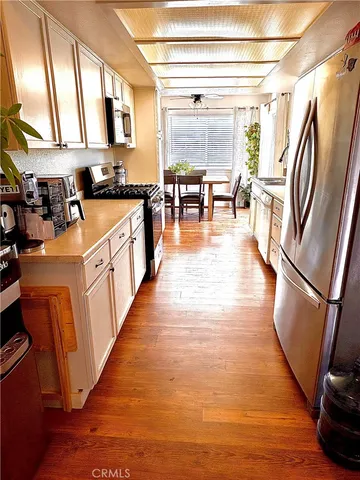 a kitchen with stainless steel appliances granite countertop a refrigerator a stove top oven a sink and dishwasher with wooden floor