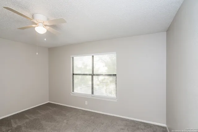 an empty room with a window and a fan