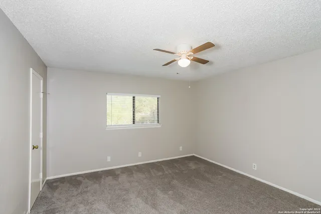 an empty room with a window and a fan