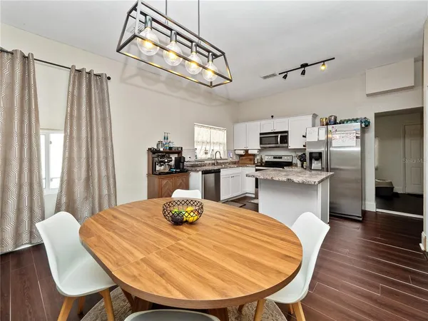 a kitchen with stainless steel appliances wooden floor dining table and chairs