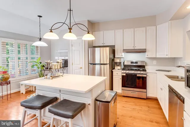 a kitchen with kitchen island a stove a table and chairs in it