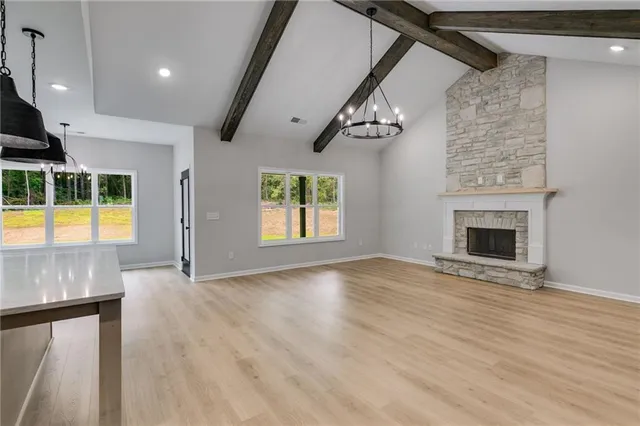 an empty room with wooden floor fireplace and windows