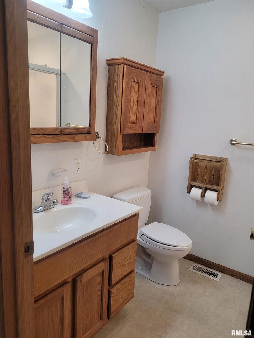 103 East Highline Road Woodlawn, IL 62898 - Photo 24 of 36 a bathroom with a toilet a sink a vanity and mirror