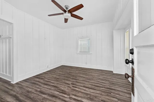 an empty room with wooden floor and a ceiling fan