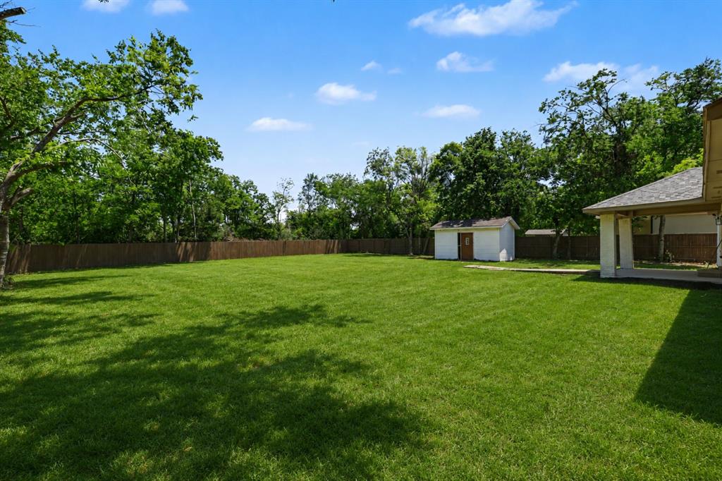 307 Dixon Street Terrell, TX 75160 - Photo 31 of 32 Expansive green lawn with mature perimeter trees, a privacy fence, and a white storage shed