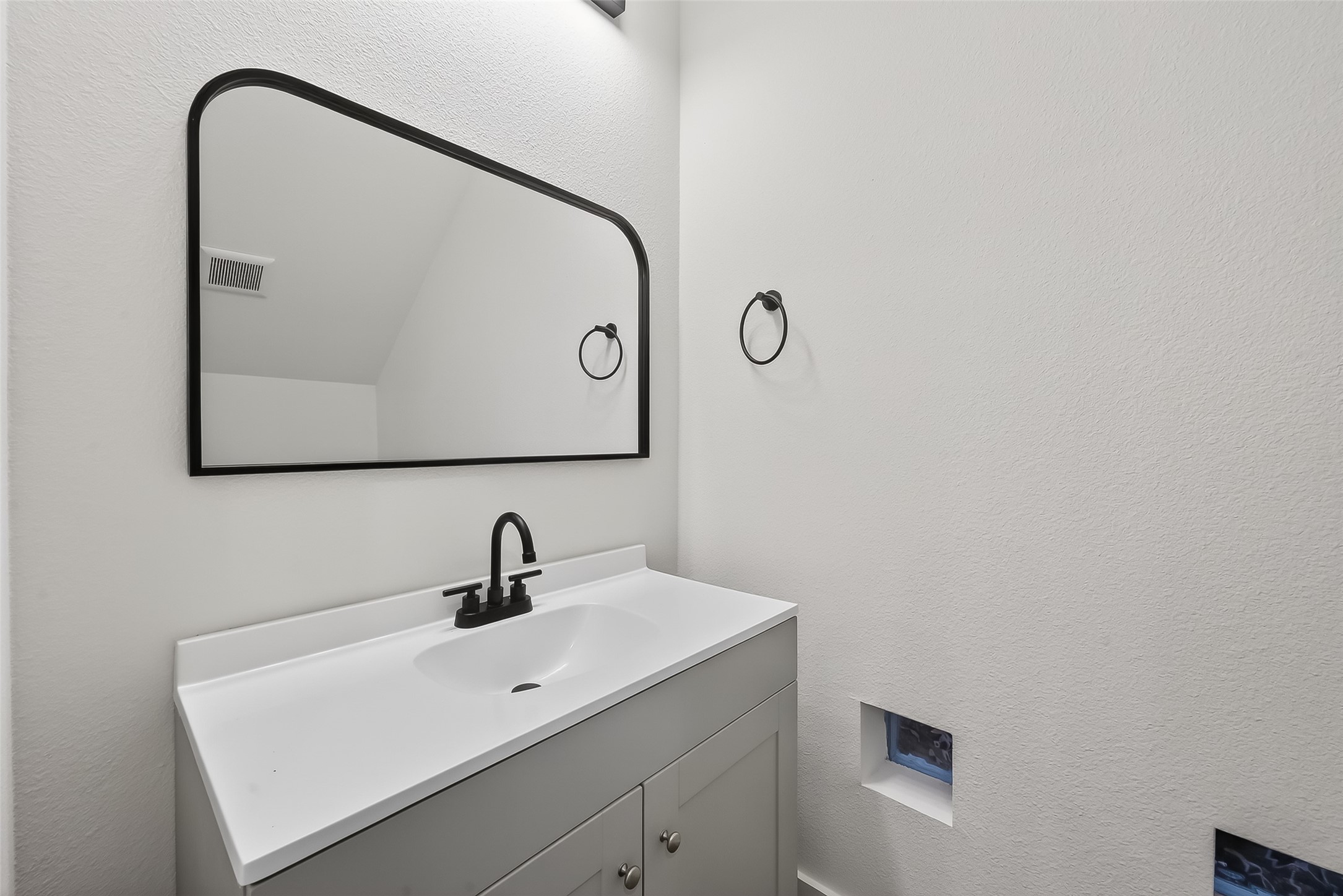 3514 Good Hope Street, Unit B Houston, TX 77021 - Photo 11 of 26 Modern powder room, on first floor, with a sleek white vanity, black faucet, and a large rectangular mirror. Minimalist design with white walls and a small window for natural light.