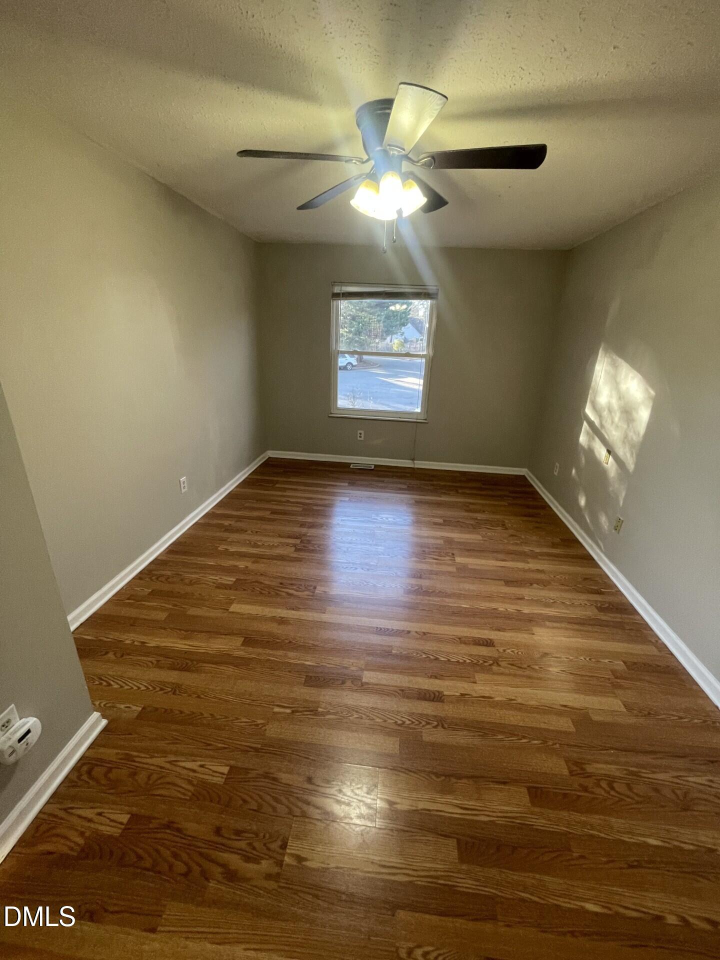 8920 Taymouth Court Raleigh, NC 27613 - Photo 14 of 20 a view of an empty room with chandelier fan and wooden floor