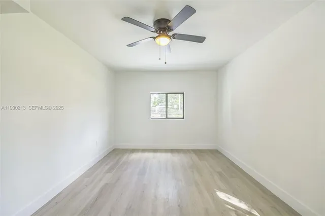 an empty room with wooden floor and ceiling fan