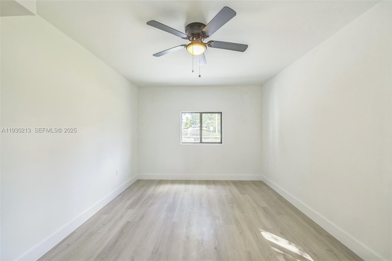 9055 Northwest 33rd Avenue Miami, FL 33147 - Photo 21 of 32 an empty room with wooden floor and ceiling fan