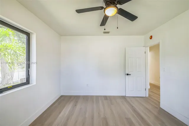 a view of an empty room with a window and wooden floor
