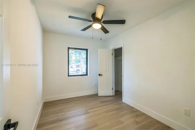 an empty room with ceiling fan and window