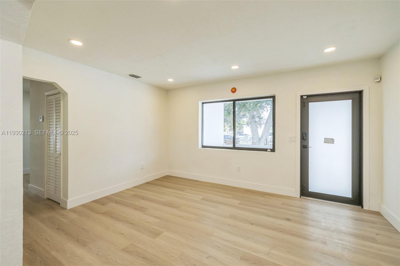 9055 Northwest 33rd Avenue Miami, FL 33147 - Photo 8 of 32 an empty room with wooden floor and windows