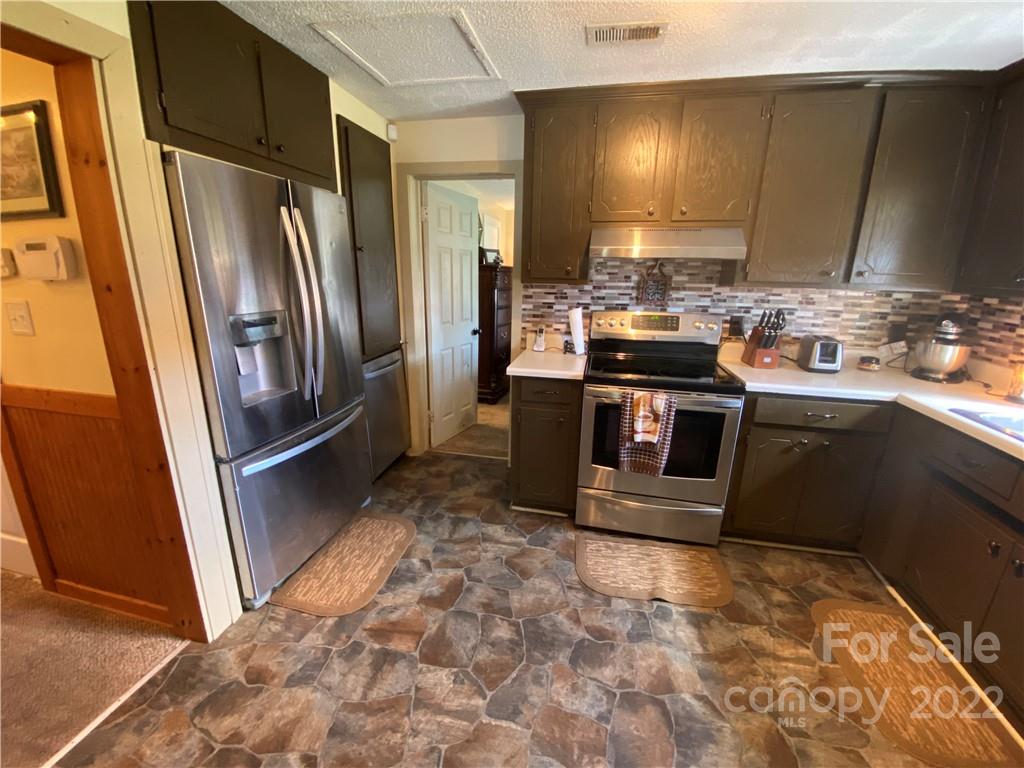 254 Landrum Road Tryon, NC 28782 - Photo 11 of 24 a kitchen with stainless steel appliances granite countertop a stove a refrigerator and a sink