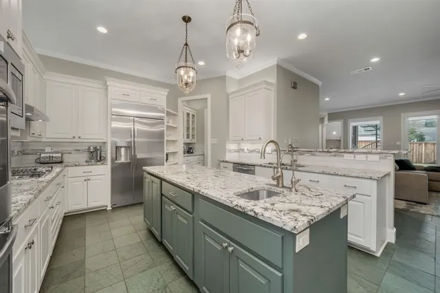 a kitchen with granite countertop stainless steel appliances a sink stove and cabinets