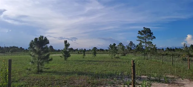 a view of a field with a house in background