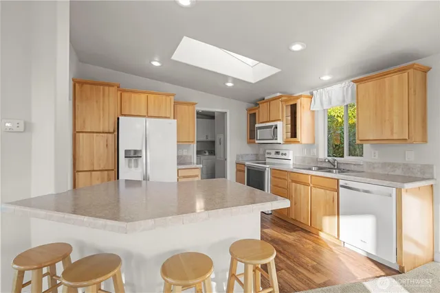 a large kitchen with stainless steel appliances granite countertop a lot of counter space and wooden floors