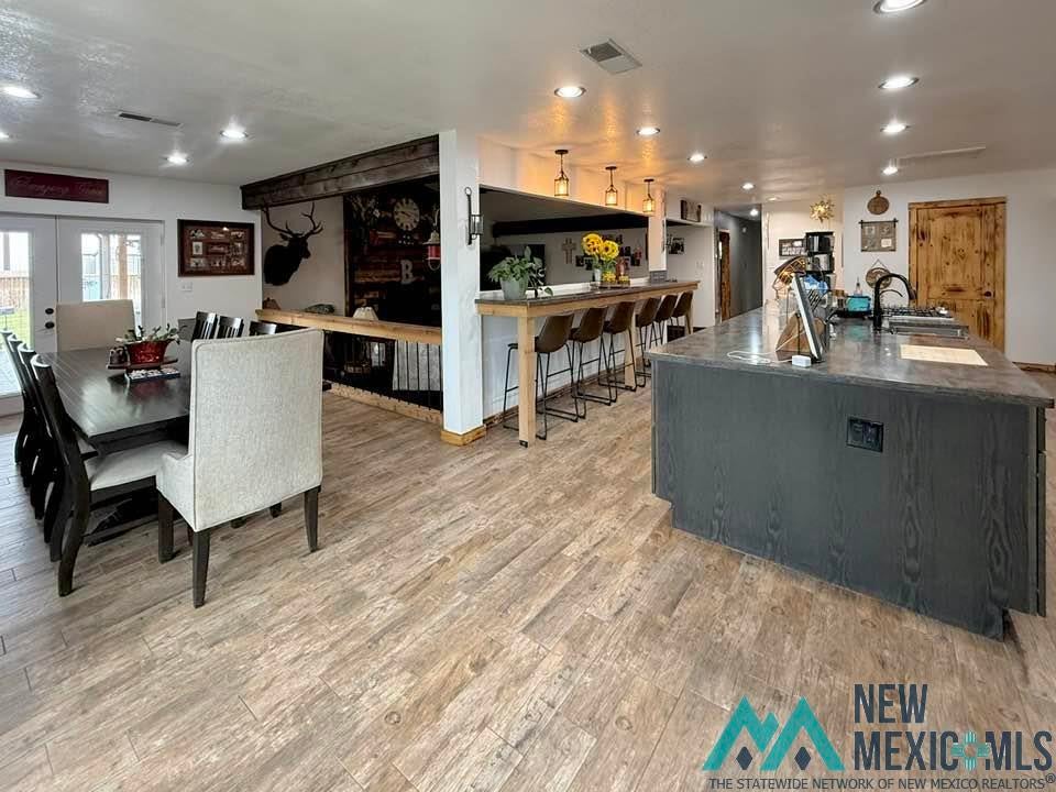 5404 Sioux Road Carlsbad, NM 88220 - Photo 23 of 100 Spacious open-concept living area featuring wood-finish flooring throughout, a large kitchen island with a dark wood-grain finish, and a breakfast bar with pendant lighting