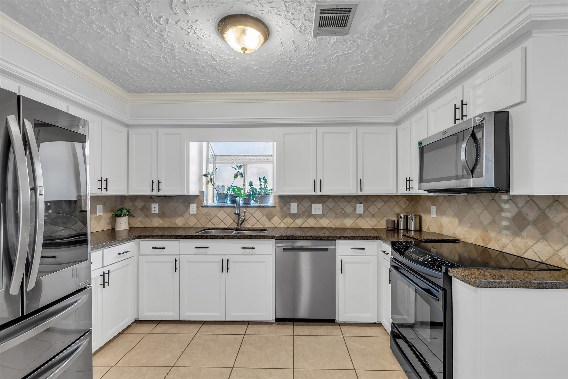 24102 Northcrest Drive Spring, TX 77389 - Photo 7 of 31 Discover the heart of this home with a spacious kitchen featuring gleaming stainless steel appliances, ample cabinetry, and elegant tile backsplash, perfect for culinary adventures.