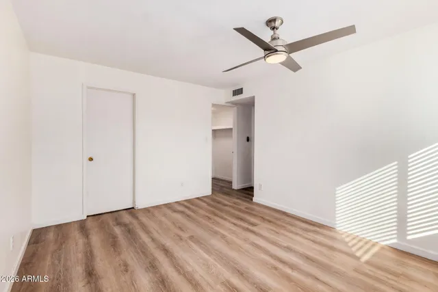 an empty room with wooden floor ceiling fan and windows