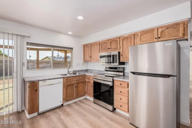 a view of kitchen with stainless steel appliances wooden floor and large window