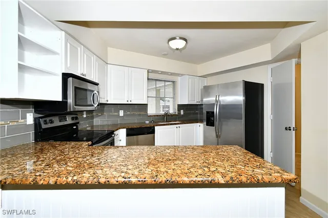 a kitchen with granite countertop white cabinets and stainless steel appliances