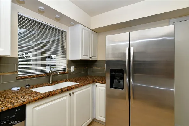 a kitchen with granite countertop white cabinets and a stove a oven with wooden floor