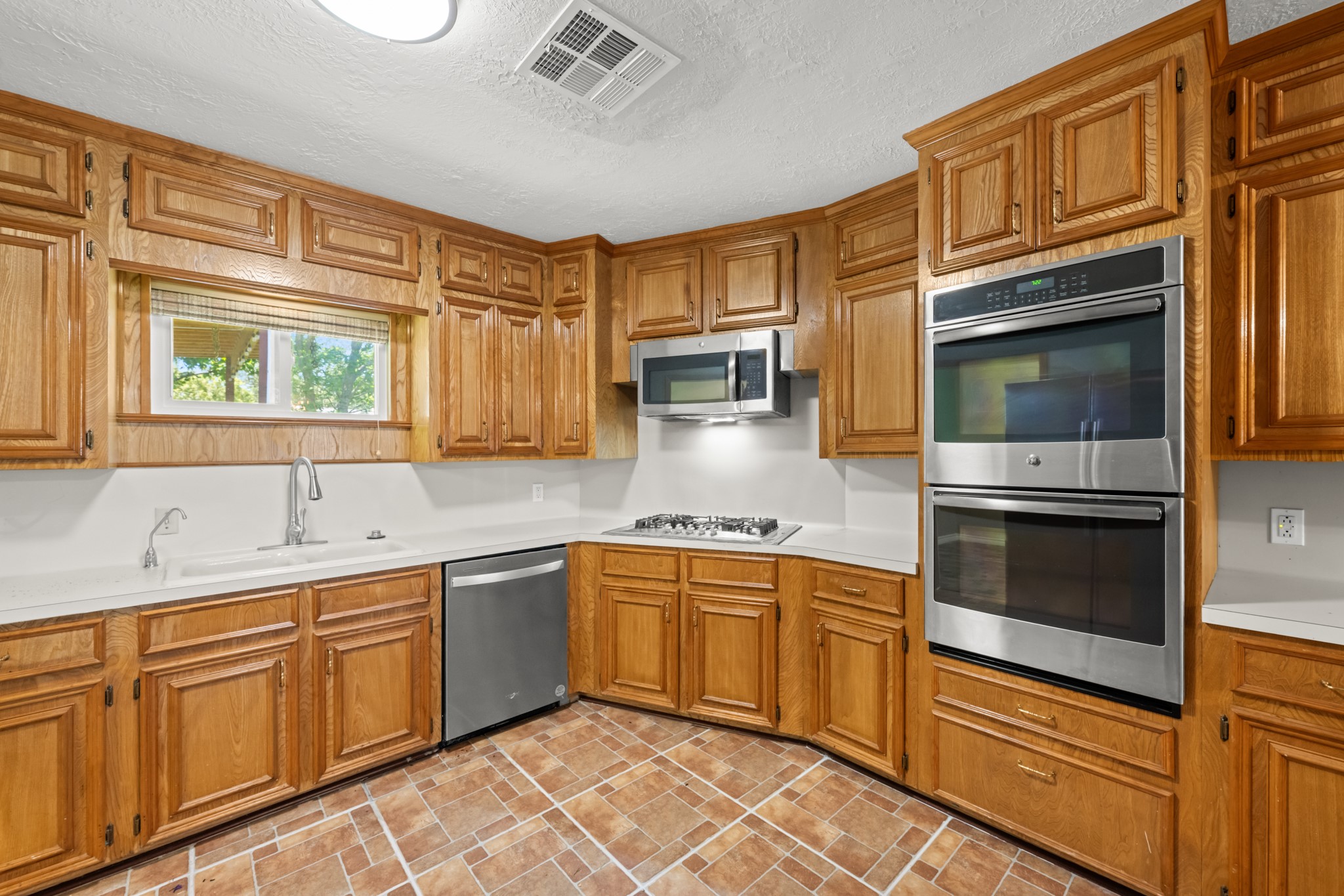616 Cannan Drive Angleton, TX 77515 - Photo 15 of 49 Thoughtfully designed for both everyday living and entertaining, this kitchen features abundant custom cabinetry, sleek countertops, a gas cooktop, and built-in double ovens. Stainless steel appliances and extensive storage provide the perfect blend of style, convenience, and functionality.