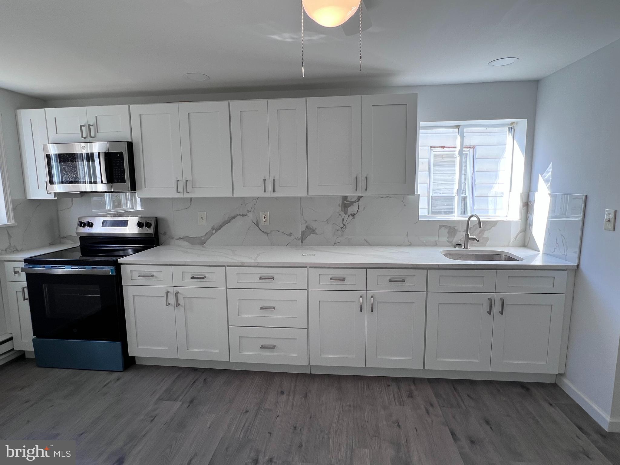 2117 West 4th Street Chester, PA 19013 - Photo 10 of 35 a kitchen with stainless steel appliances granite countertop a stove a sink and white cabinets