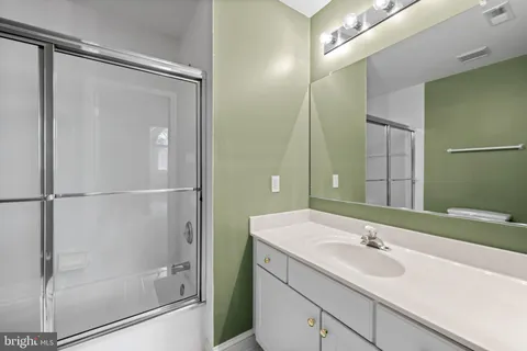 a bathroom with a shower sink vanity and mirror