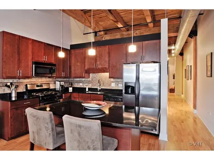 a kitchen with stainless steel appliances granite countertop a refrigerator a stove top oven a sink with island and chairs