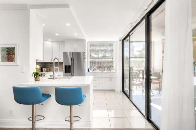 a kitchen with stainless steel appliances kitchen island granite countertop a refrigerator a oven a sink and a dining table with garden view