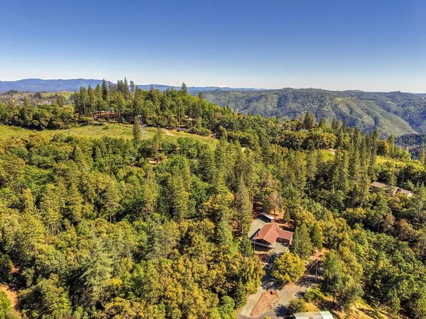 an aerial view of house with yard and mountain view in back