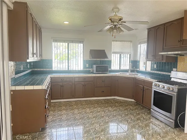 a kitchen with stainless steel appliances granite countertop a stove a sink and a microwave