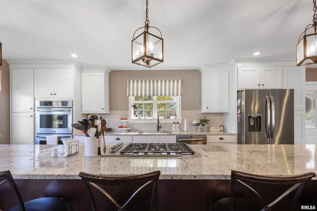 a kitchen with stainless steel appliances granite countertop a stove a sink a refrigerator and a cabinets