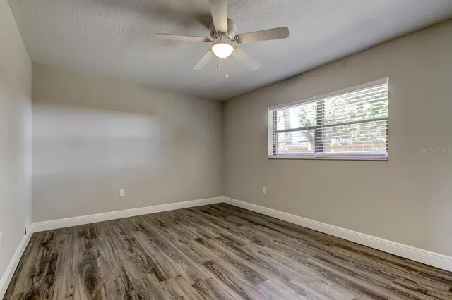 an empty room with wooden floor and a ceiling fan