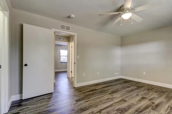 an empty room with wooden floor and a ceiling fan